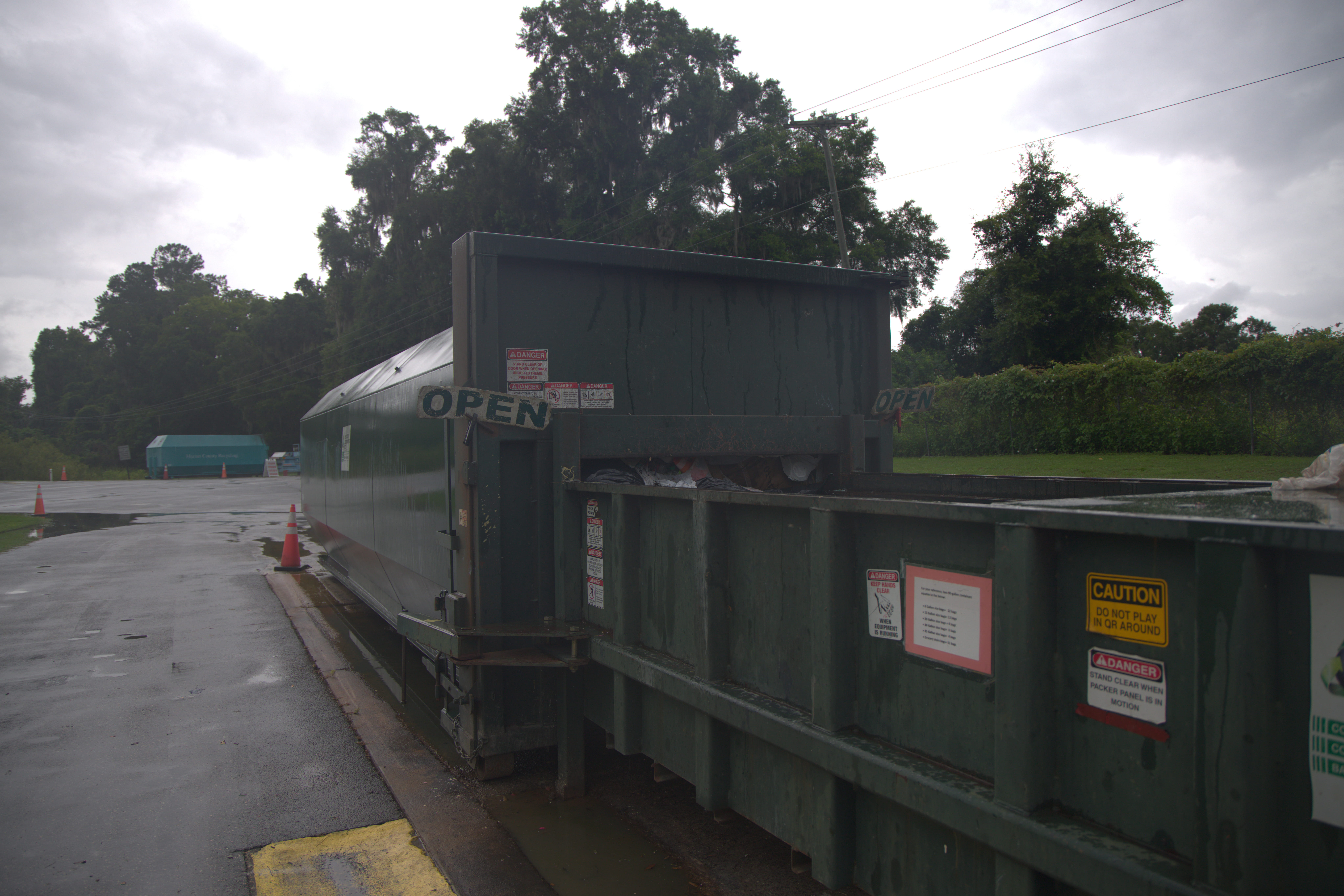 An image of a trash compactor. It has a sign on it that says open.